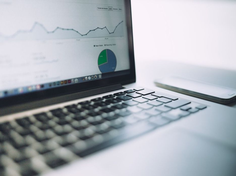 A laptop showing an analytics dashboard with charts and graphs