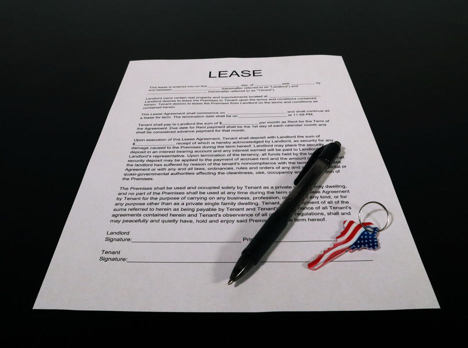Lease agreement document with pen and American flag keychain on a black table