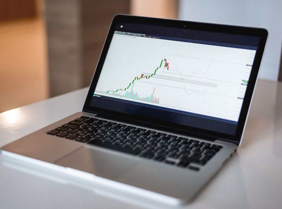 Close-up of a laptop showing a financial trading graph