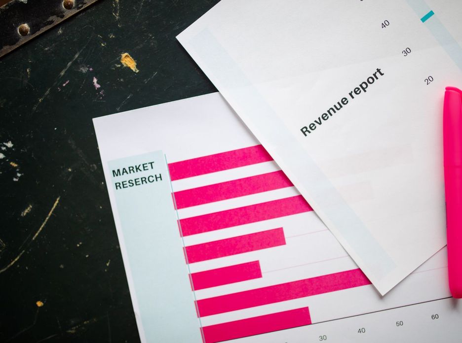 Close-up of market research charts and a revenue report with a pink pen on a desk