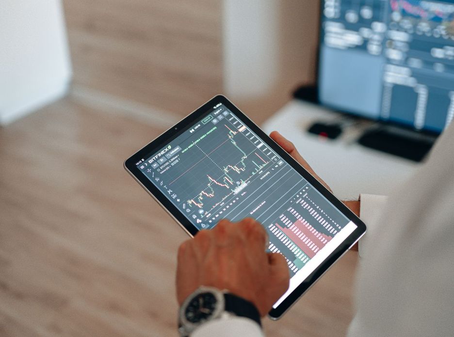 Close-up of hands using a tablet for online trading and market analysis