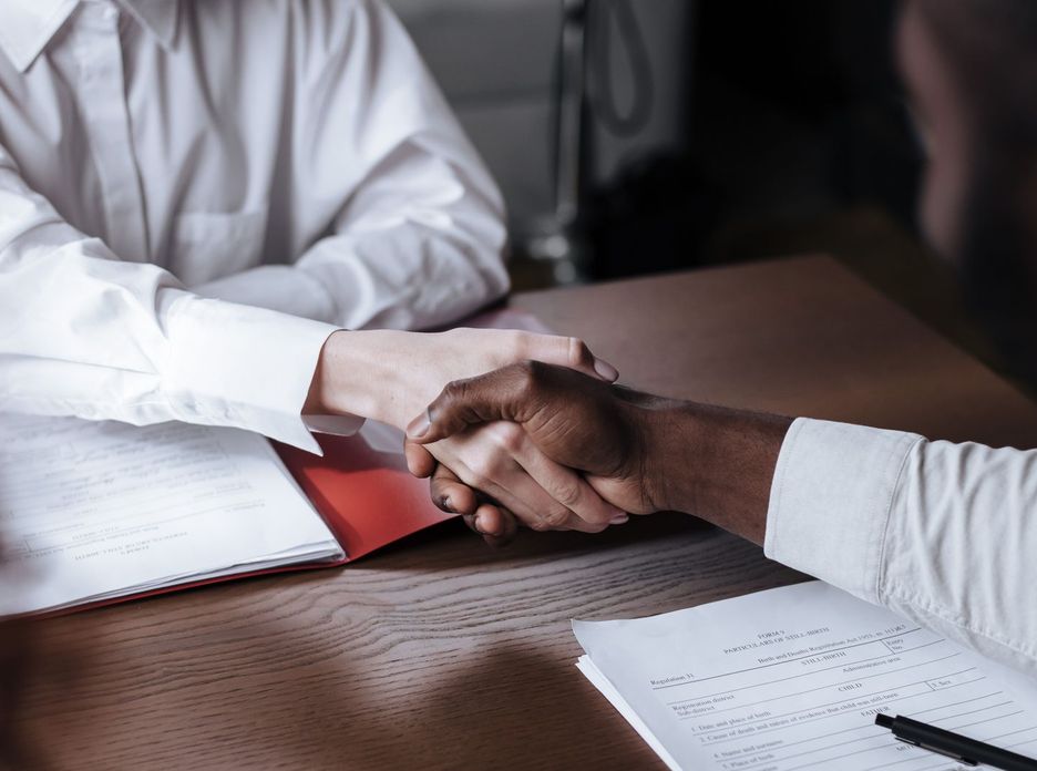 Close-up of a diverse business handshake over documents