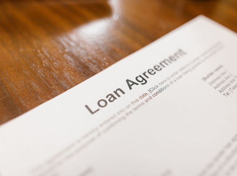 Detailed loan agreement document close-up on a wooden table representing legal and financial concepts