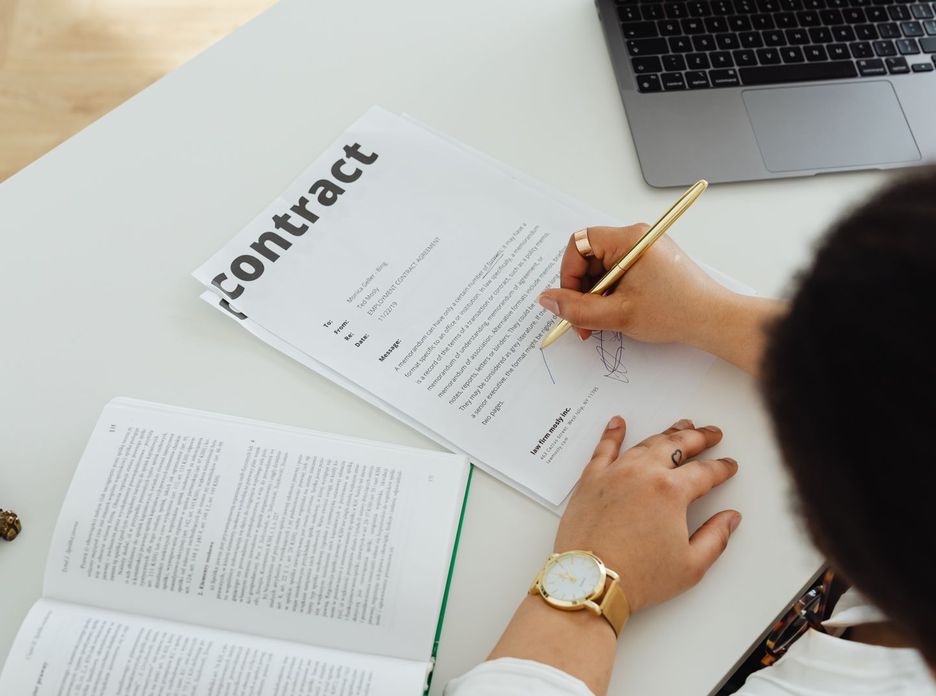 Professional signing a business contract at a modern desk setup for office work