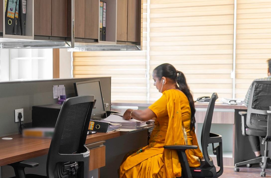 A woman in yellow working at her desk in a modern open-plan office