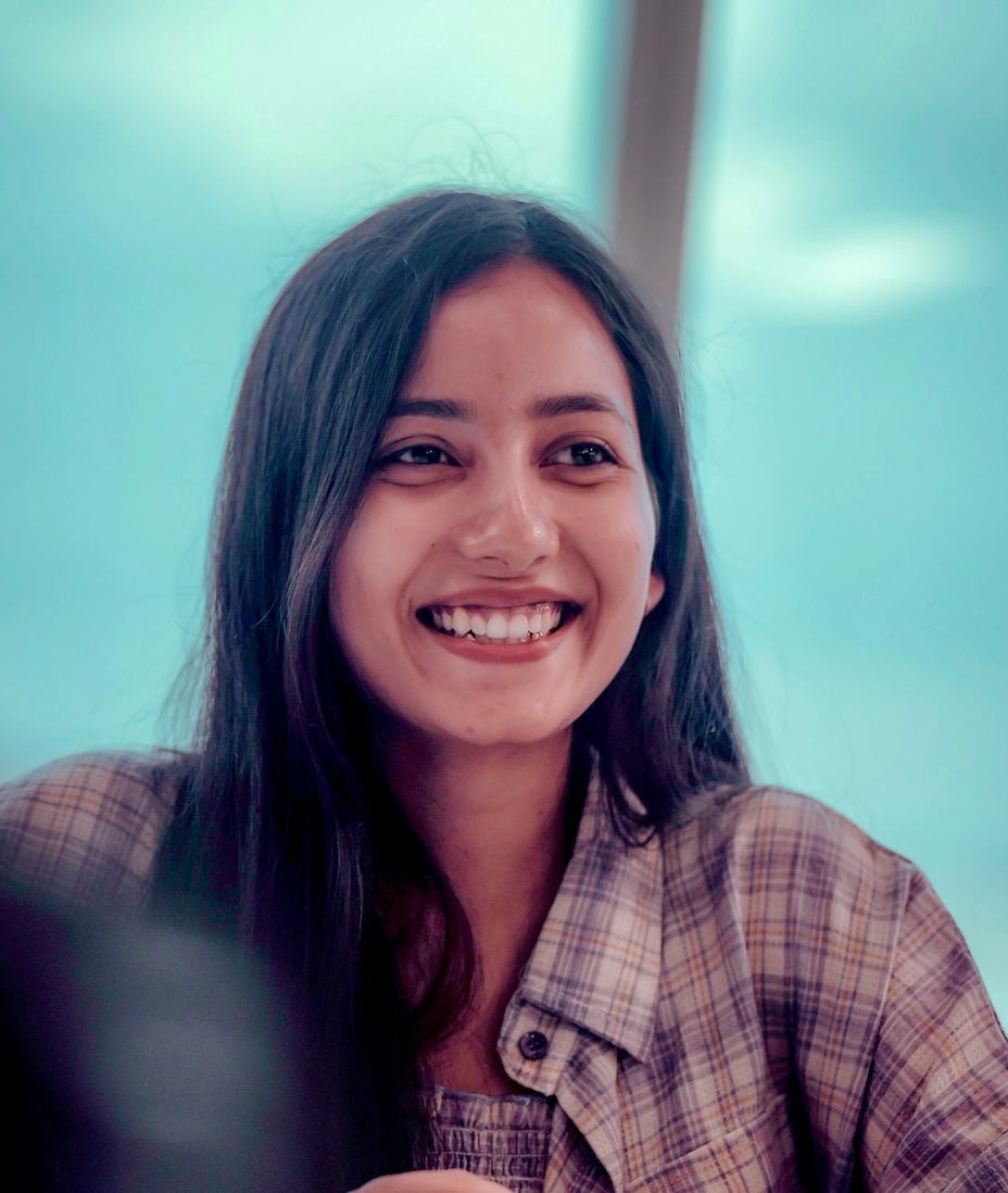A smiling woman in a checked shirt at work in an office
